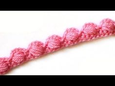 a crocheted pink piece of yarn on a white surface with the end stitched together