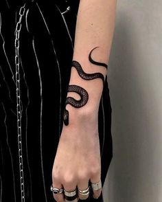 a person with a snake tattoo on their arm holding onto a chain and wearing rings