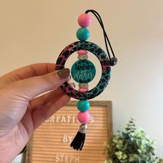 a hand holding a beaded necklace with an animal print circle and tassels