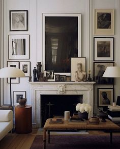 a living room filled with furniture and framed pictures on the wall above a fire place