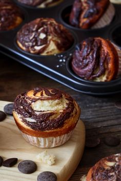 chocolate swirl muffins sitting on top of a wooden cutting board