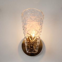 a light that is on the wall with a glass vase in it's center