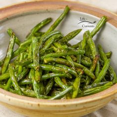 a bowl filled with green beans on top of a table