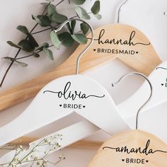 three wooden hangers with names on them and some flowers in the bottom right corner