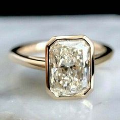 a close up of a diamond ring on a marble surface with white and gold accents