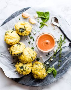 several scones on a plate with dipping sauce and fresh herbs next to the top