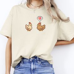 Consider the Stardew Valley Chicken Love T-Shirt, a cozy unisex cotton tee perfect as a gift for your gamer friend or family member. This gaming shirt, featuring pixel art, adds a touch of coziness to their gaming wardrobe, making it ideal for relaxed gaming sessions. Details: -- 100% Cotton -- Tearaway neck label -- Multiple Colors and Sizes -- Unisex Crewneck How to Order: 1. Select Size 2. Select Color 3. Add To Cart 4. Select Shipping Method Shipping:  :: Production takes 1-2 Days :: Express Casual Cartoon Print T-shirt For Gifting, Casual Cartoon Print T-shirt For Gift, Casual T-shirt With Cartoon Print For Gift, Short Sleeve Cartoon Print Top As Gift, Cartoon Print Short Sleeve Top For Gift, Short Sleeve Tops With Cartoon Print For Gift, Cute Relaxed Fit T-shirt For Gift, Casual Crew Neck Shirt Perfect For Gifts, Short Sleeve T-shirt With Cartoon Print For Gift