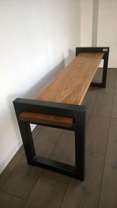 a wooden bench sitting on top of a hard wood floor next to a white wall