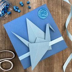 an origami bird on a blue card surrounded by scissors