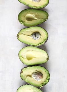 an avocado is cut in half and placed on a white surface with other pieces