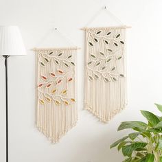 two wall hangings made out of macrame with leaves and branches on them