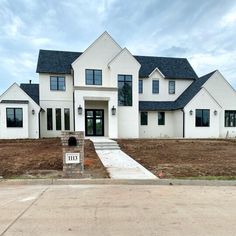 a large white house sitting on the side of a road next to a dirt field