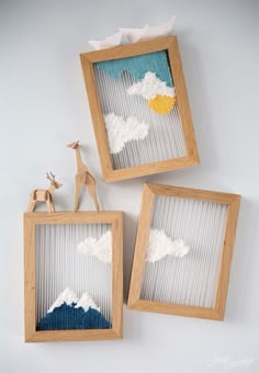 two wooden frames with white clouds and giraffes in them on the screen