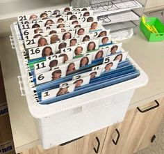 a plastic container filled with lots of photos and folders on top of a counter