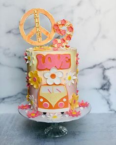 a peace sign on top of a colorful cake with flowers and daisies around it