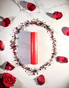 a red candle surrounded by rose petals and petals