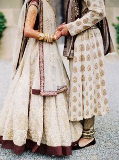 two people standing next to each other in wedding outfits and holding hands with each other