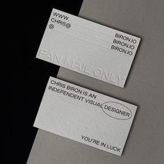 two white business cards sitting on top of each other next to each other with black lettering