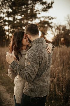 a man and woman kissing in the middle of a field