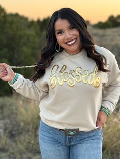 THIS IS FROM OUR TEXAS TRUE THREADS COLLECTION AND WILL SHIP WITHIN 1-2 BUSINESS DAYS FROM THE WAREHOUSE. IF YOU WOULD LIKE LOCAL PICKUP, I WILL EMAIL YOU AS SOON AS IT ARRIVES As we approach this time of the year where we seem to truly take time to be thankful for all that we are blessed with, this sweatshirt couldn't be more perfect for that! Shown on a Cotton Heritage cream colored sweatshirt Blessed in Metallic Gold Puff Ink Unisex Fit, Runs true to size with a relaxed fit I am a size 6/8 an Puff Sweatshirt, Puff Design, Dresses Western, Colorful Sweatshirt, Western Graphic Tees, Express Gratitude, Red River, Be Thankful, Sweaters Hoodies