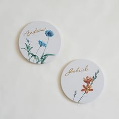 two badges with flowers on them sitting next to each other