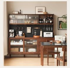 a kitchen area with a table and shelves filled with bottles, wine glasses, and other items