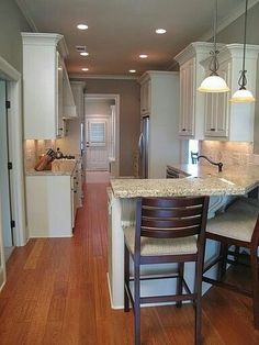 a kitchen with white cabinets and an island next to a dining room table in it