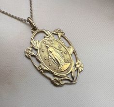 A beautiful genuine vintage Blessed Virgin Mary medal, French Mother Mary lucky charm, religious catholic holy charm, the reverse is engraved with initials from previous owner, lifetimes ago (see photo 2). Very nicely done, in good vintage condition, ideal for necklace, would make a nice gift for someone special! Floats from approx. 17 inch long vintage 925 silver cable type chain! Material: solid silver - gold plated vermeil Total weight: 5.7g Measures: approx. 35 x 22 mm (1.4 x 0.8 inch)  PLEASE LOOK AT THE PICTURES, THEY ARE PART OF THE DESCRIPTION AND ARE THE ACTUAL ITEM YOU WILL RECEIVE. ALL OUR ITEMS ARE IN WORN, VINTAGE CONDITION. Miraculous Medal Medallion For Commemoration, Spiritual Wedding Miraculous Medal Jewelry, Engraved Spiritual Medallion Jewelry, Antique Miraculous Medal Necklace As Gift, Antique Miraculous Medal Pendant Jewelry, Yellow Gold Crucifix With Miraculous Medal, Antique Jewelry With Miraculous Medal For Collectors, Miraculous Medal Pendant For Wedding, Wedding Miraculous Medal Pendant