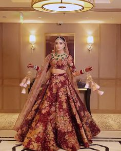 a woman in a red and gold bridal gown standing on a marble floor with chandelier