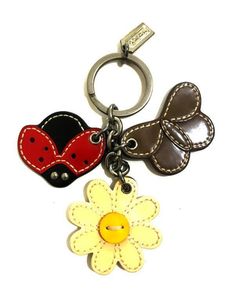 two little ladybugs and a flower are on the keychain, one has a leather tag attached to it