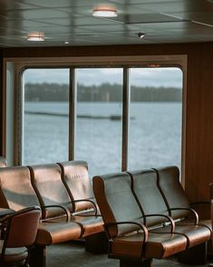 empty chairs are sitting in front of a window overlooking the water on a cruise ship