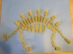 an animal made out of pasta sitting on top of a blue paper sheet with holes in it