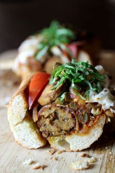 an open sandwich with meat, vegetables and sauce on it sitting on a cutting board