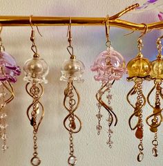 Add a touch of the ocean to your jewelry collection with these stunning Jelly Fish Dangle Earrings. These unique earrings feature intricately designed jellyfish charms that will sway and shine with every movement. Perfect for anyone who loves marine life or wants to add a whimsical touch to their outfit. These earrings are sure to make a splash and are a great gift for any ocean lover. Whimsical Dangle Jewelry For Party, Whimsical Party Dangle Jewelry, Whimsical Adjustable Iridescent Jewelry, Ocean-inspired Gold Jewelry For Party, Handmade Whimsical Clear Jewelry, Whimsical Handmade Clear Jewelry, Whimsical Jewelry With Dangling Charms For Party, Jellyfish Earrings, Grass Valley