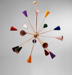 a multicolored chandelier hanging from the ceiling with wooden sticks sticking out of it