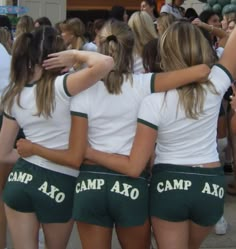 a group of girls in green and white shorts standing together with their arms around each other