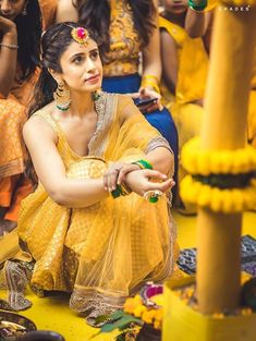 a woman sitting on the ground in front of other people wearing yellow and green outfits