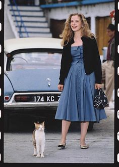 a woman standing next to a cat in front of a car