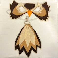 an owl mask and keychain hanging on a white board with black trimmings