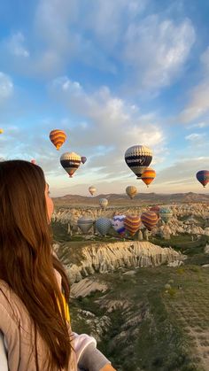 a woman looking out at hot air balloons in the sky