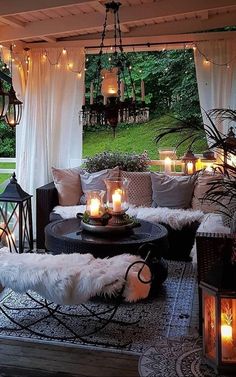 an outdoor living room with candles lit on the table and couches covered in fur