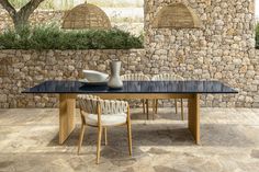 a table and chairs in front of a stone wall