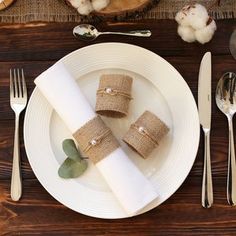 napkins wrapped in burlap are sitting on a white plate with silverware