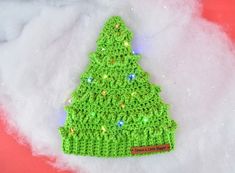 a green crocheted christmas tree ornament sitting on top of white snow