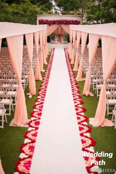 the aisle is lined with pink and red flowers, along with drapes draped over it