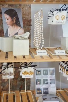 jewelry is displayed on wooden shelves in a display case with pictures and necklaces hanging from them