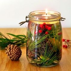 a glass jar filled with pine cones and evergreen needles on top of a wooden table