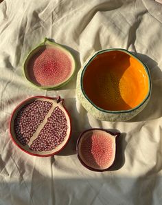 three bowls filled with different types of fruit on top of a white cloth covered table