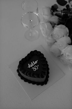 a heart shaped cake sitting on top of a table next to wine glasses and flowers