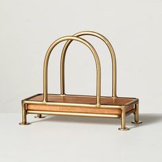 a gold metal and wood holder with two handles on each side, sitting on a white surface